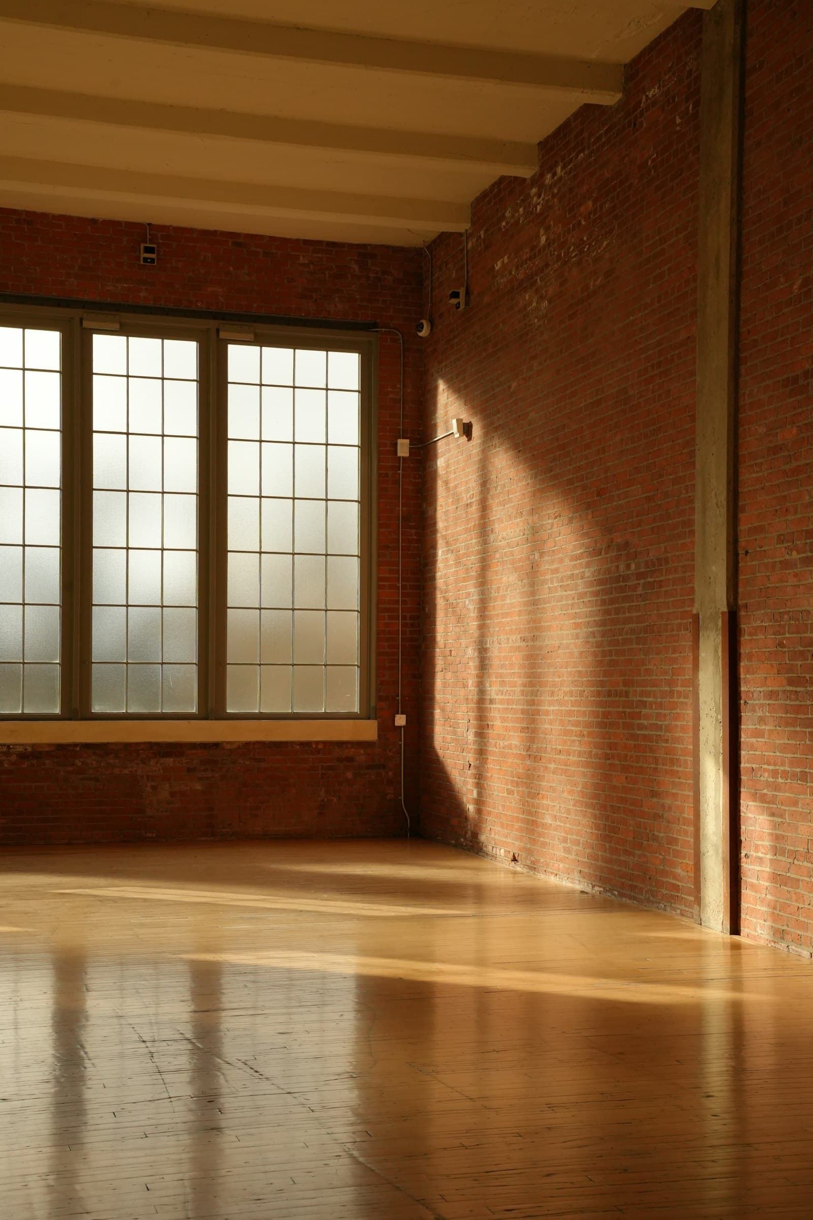 Late afternoon light falling across the wood floor of an empty room.